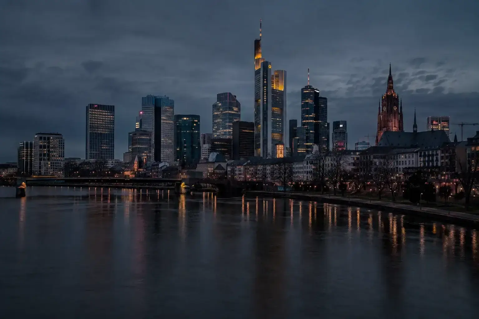 Frankfurter Skyline mit beleuchteten Hochhäusern über dem Main